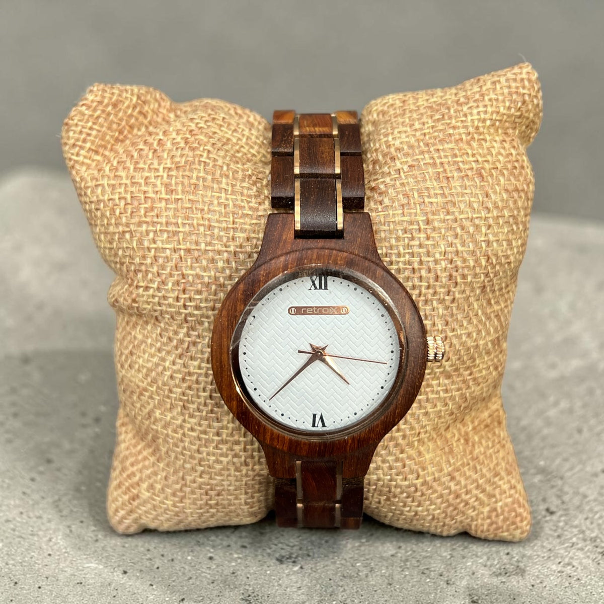 Retro X women's dark wood watch with white textured dial and rose gold accents, shown on a burlap pillow