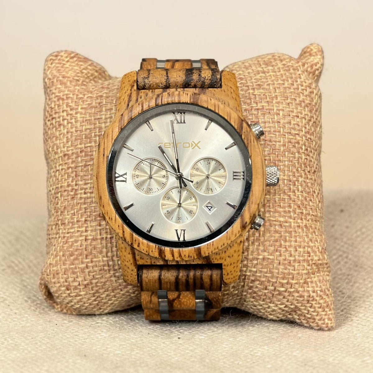 Retro X zebra wood chronograph watch with silver dial, roman numerals, three subdials, date window and silver-tone pushers, shown on a burlap pillow